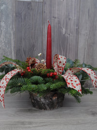 centre de table de Noël avec une bougie rouge, des rubans et des baies.